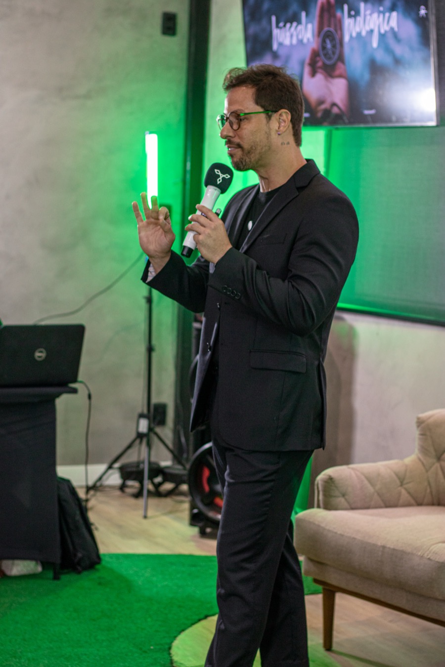 kerk conduzindo uma edição do café com branding ao microfone, sob luz verde